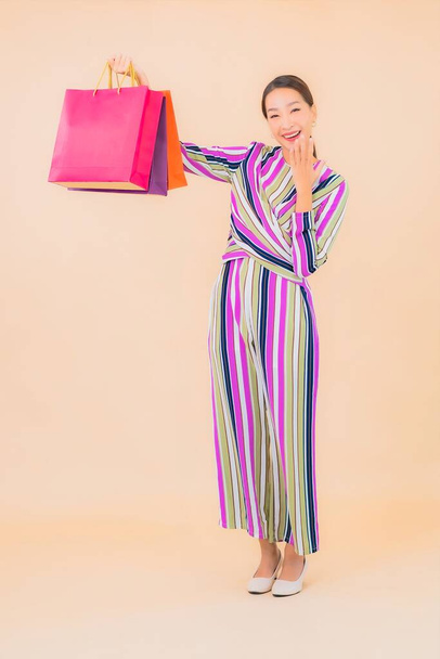 Portrait beautiful young asian woman with colorful shopping bag on color isolated background - Photo, Image