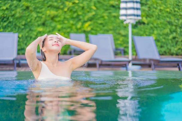 Retrato bela jovem asiática mulher desfrutar ao redor piscina ao ar livre com vista mar oceano em viagem de férias - Foto, Imagem