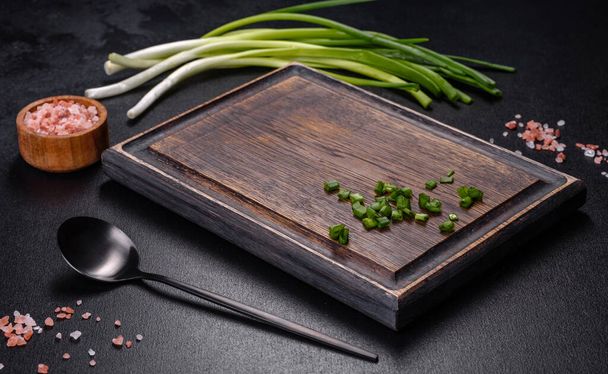 Black metal spoon and rectangular cutting board on black concrete background. Preparing for Cooking - Foto, afbeelding