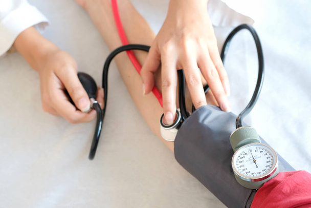 Dokter vrouw controleer bloeddruk monitor en hartslagmeter manometer. Gezondheidszorg en medisch concept - Foto, afbeelding