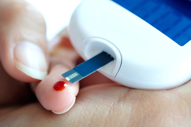 la mano delle persone controlla il diabete e il monitoraggio della glicemia alta con il manometro digitale. Sanità e concetto medico - Foto, immagini