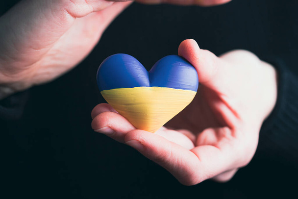 Heart shaped flag of Ukraine in female hands. The concept of solidarity with the citizens of Ukraine. - Valokuva, kuva