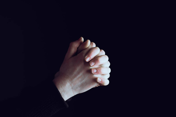 Prier les mains avec foi en la religion et la croyance en Dieu sur fond sombre. Pouvoir d'espoir ou d'amour et de dévotion
. - Photo, image