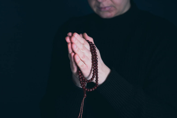 Religious young woman praying to God, on dark background. - Valokuva, kuva