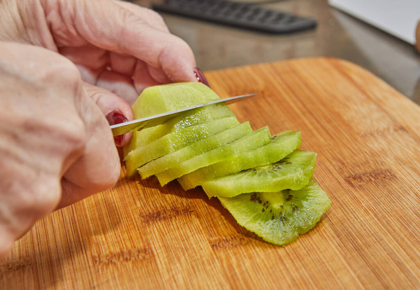 Chef is preparing kiwi pie, cut the kiwi into slices. - Foto, immagini