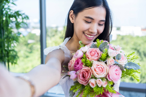 Valentine's day concept,Selfie of Happy of smiling Asian young female sitting at a table food holding a bouquet of roses at in the restaurant background - Foto, Bild