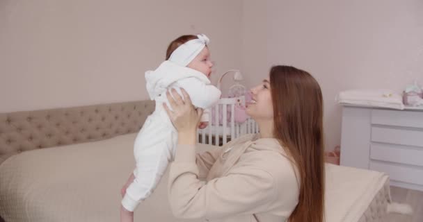Feliz joven madre caricia tiernamente y besa al bebé recién nacido, sosteniéndola en sus brazos - Metraje, vídeo