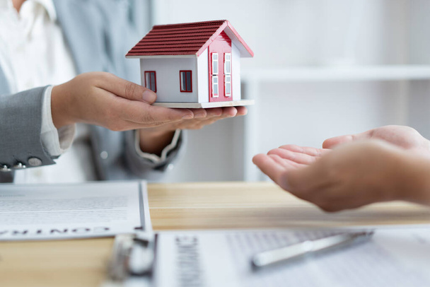 Concetto di assicurazione l'agente immobiliare che detiene un modello di casa e lo dà al suo cliente. - Foto, immagini