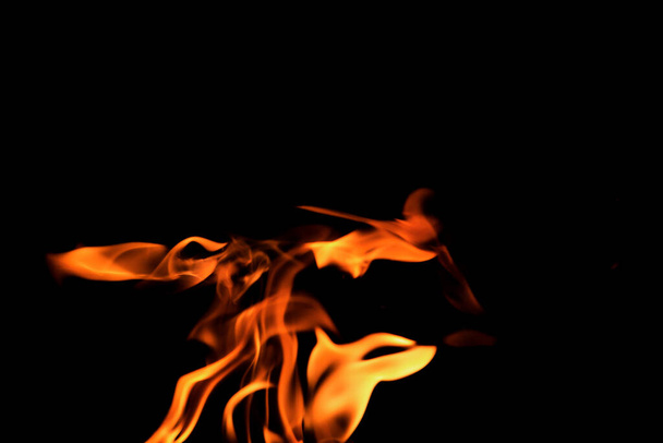 Close up burning flames on black background for graphic design or wallpaper. Red and yellow, heat energy igniting fuel during night. Abstract shaped fire used for cooking. - Fotó, kép