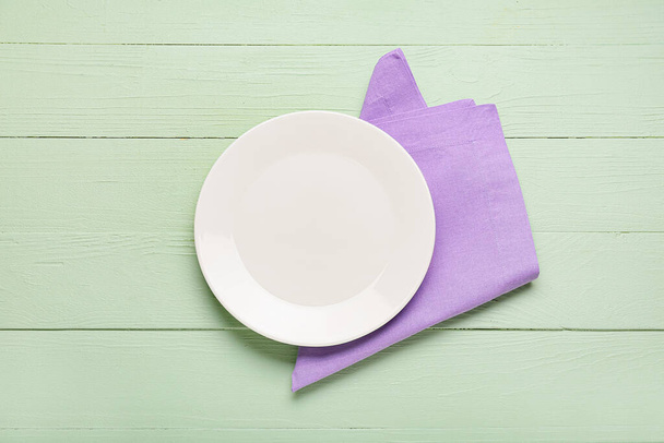 Plate with napkin on color wooden background - Photo, Image