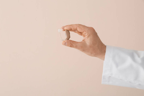 Χέρι του γιατρού με ακουστικό βαρηκοΐας σε ελαφρύ φόντο - Φωτογραφία, εικόνα