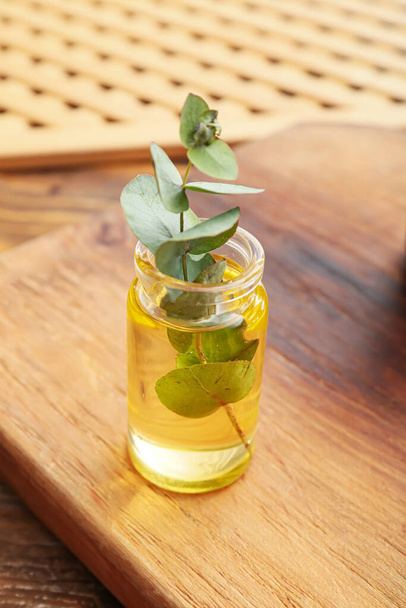 Пляшка натуральної ефірної олії евкаліпта на дерев'яному фоні
 - Фото, зображення
