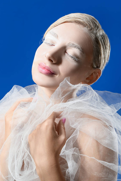 Beautiful young woman with creative makeup and veil on color background - Photo, Image