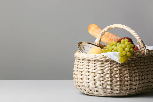ウィッカーバスケットともにおいしい食べ物ピクニックのための灰色の背景 - 写真・画像