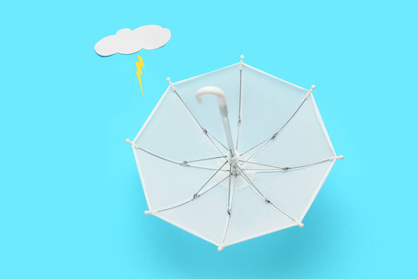 Composición con paraguas, nube de papel y relámpago sobre fondo de color - Foto, imagen