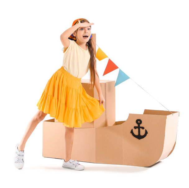 Petite fille drôle jouant avec le navire en carton sur fond blanc - Photo, image