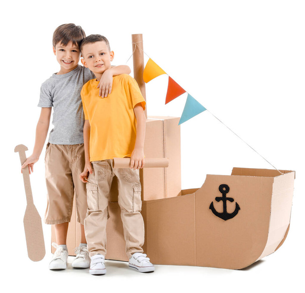 Funny little boys playing with cardboard ship on white background - 写真・画像