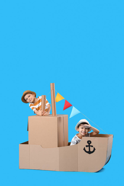 Engraçado meninos brincando com o navio de papelão no fundo azul - Foto, Imagem