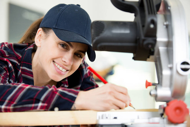 happy woman in builder clothers holding circular saw - Foto, Bild