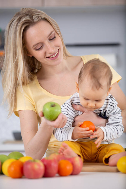 woman and baby in the kitchen making healthy fruit salad - Foto, Bild