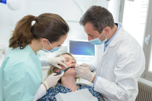 dentist and nurse are curing a female patient - Foto, Imagen