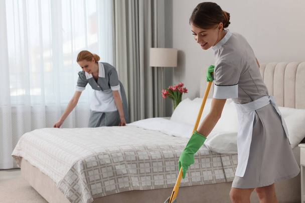 Professional chambermaids cleaning up bedroom in hotel - Valokuva, kuva