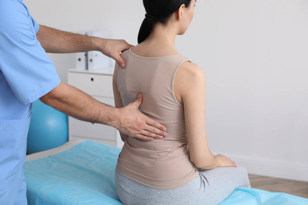 Orthopedist examining woman's back in clinic, closeup. Scoliosis treatment - Фото, изображение