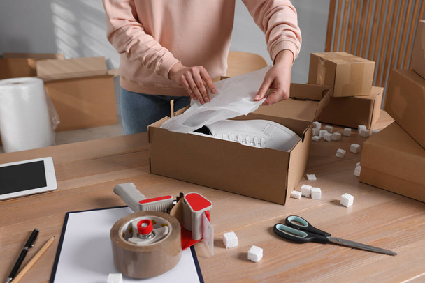 Seller packing shoes into cardboard box at table in office, closeup. Online store - Photo, Image