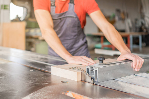 Μη αναγνωρίσιμος ξυλουργός που εργάζεται σε συρόμενο τραπέζι πριονιού - Φωτογραφία, εικόνα