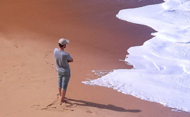 Чоловік з капелюхом дивиться в море на краю океану
 - Фото, зображення