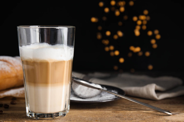 Delicious latte macchiato, croissant and coffee beans on wooden table. Space for text - Foto, imagen