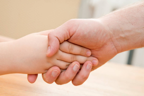 Kids hands in the fathers palms. Parenting, friendship, guardianship, upbringing, parent-child relationship, family connection. - Foto, Bild
