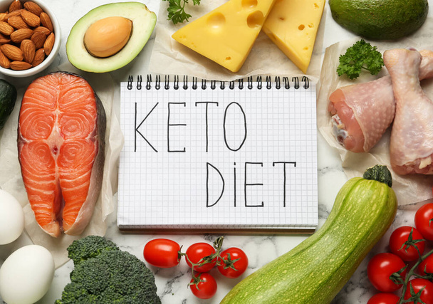 Notebook with words Keto Diet and fresh products on white marble table, flat lay - Foto, Imagen