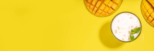 Fresh mango smoothie, yogurt, milkshake or smoothie with half slice of mango on high-colored bright background top view copy space - Fotoğraf, Görsel