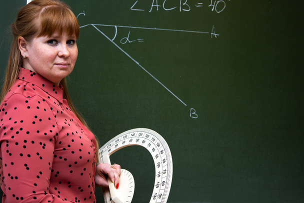 Un profesor de matemáticas explica la lección a los estudiantes cerca de la pizarra. - Foto, imagen