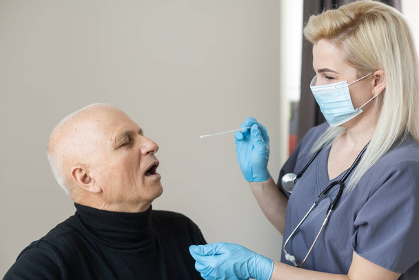 Doktor používající otisk nosu koronavirus COVID-19 s vyšším starším mužem v nemocnici. Lékařské vyšetření na COVID-19 v nemocnici. - Fotografie, Obrázek