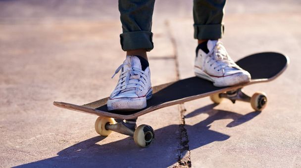 Deze sneakers zijn gemaakt om te schaatsen. Een bijgesneden shot van een vrouw staand op een skateboard. - Foto, afbeelding