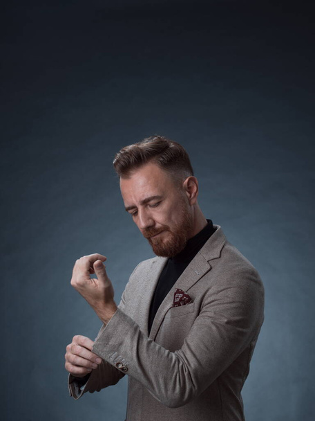 Portrait of a stylish elegant senior businessman with a beard and casual business clothes in photo studio isolated on dark background gesturing with hands - Foto, imagen