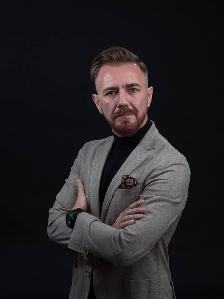 Portrait of a stylish elegant senior businessman with a beard and casual business clothes in photo studio isolated on dark background gesturing with hands - 写真・画像