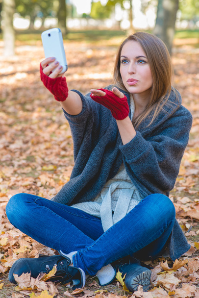 mosolygó nő vesz egy selfie, egy őszi parkban - Fotó, kép