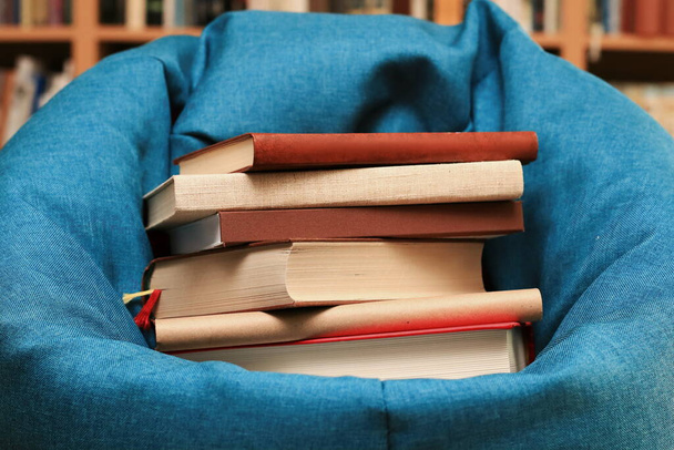 Βιβλία για την πολυθρόνα στη βιβλιοθήκη - Φωτογραφία, εικόνα