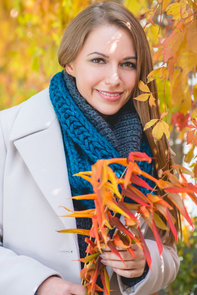 Stilvolle junge Frau pflückt Herbstblätter - Foto, Bild