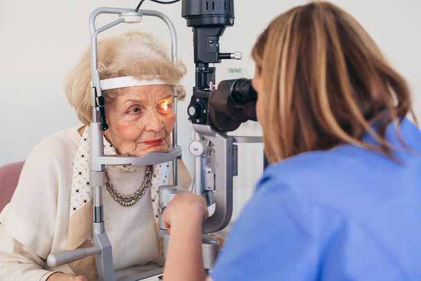 senior woman has eyesight examination in clinic - Foto, afbeelding