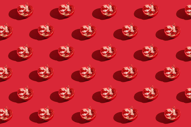 Creative pattern made of fresh pomegranates on red background with shadows. Refreshment concept. Healthy food ingredient theme. Minimal style - Fotoğraf, Görsel