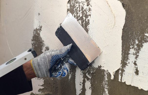 El proceso de aplicación de una masilla blanca en la pared de hormigón gris
 - Foto, Imagen
