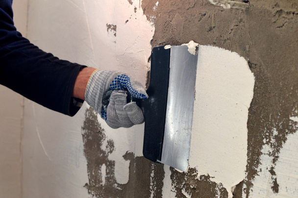 der Prozess des Auftragens eines weißen Spachtels auf eine graue Betonwand  - Foto, Bild