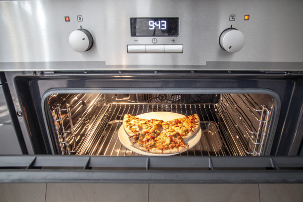 暖房準備にオーブンでピザを食べてください。 - 写真・画像