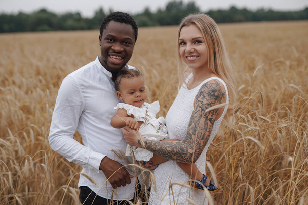 Famille multiculturelle avec un enfant en vacances dans les champs de blé - Photo, image
