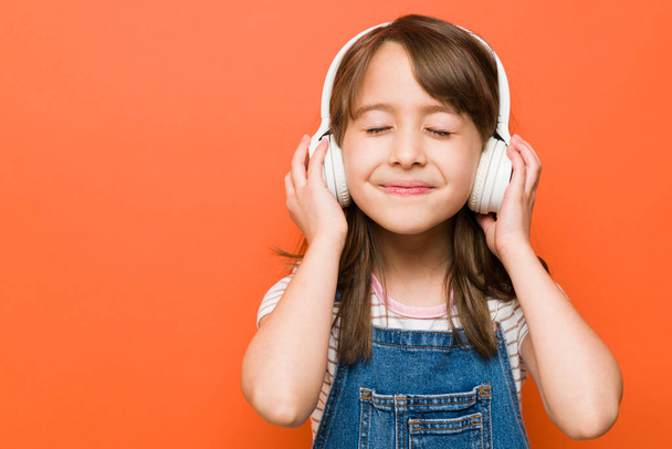 Közelkép egy csinos kis barna hallgat kedvenc zenéje visel vezeték nélküli fejhallgató - Fotó, kép