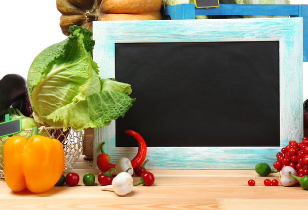 Fresh organic vegetables with chalkboard on wooden table, close up - Фото, изображение